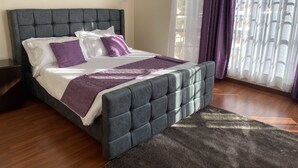 Un dormitorio con una cama grande, un espejo redondo y una ventana con cortinas.