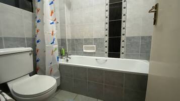 Un baño con inodoro, bañera y cortina de ducha.