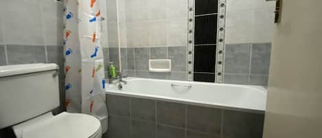 Un baño con inodoro, bañera y cortina de ducha.