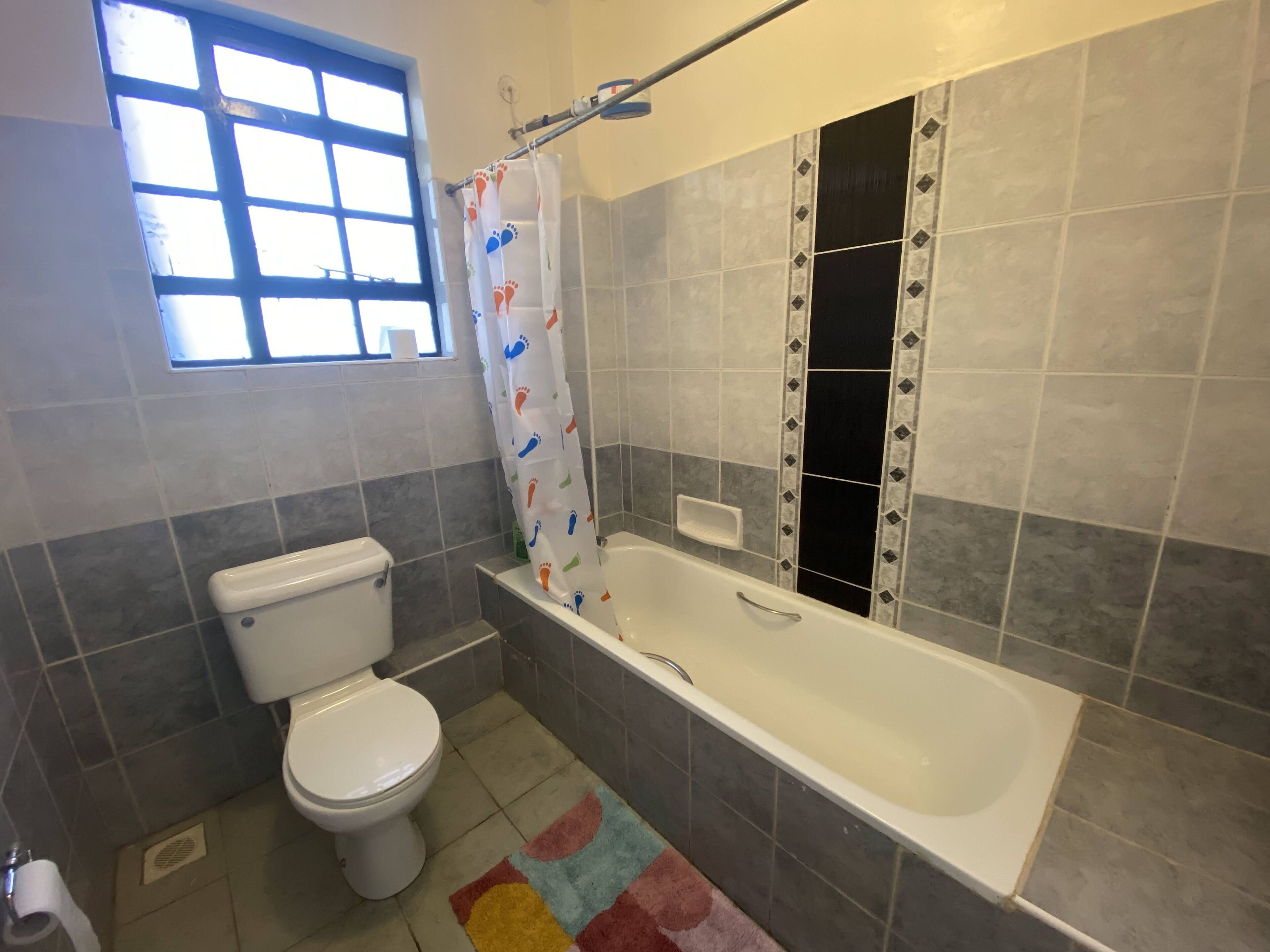Un baño con inodoro, bañera, cortina de ducha y una ventana.