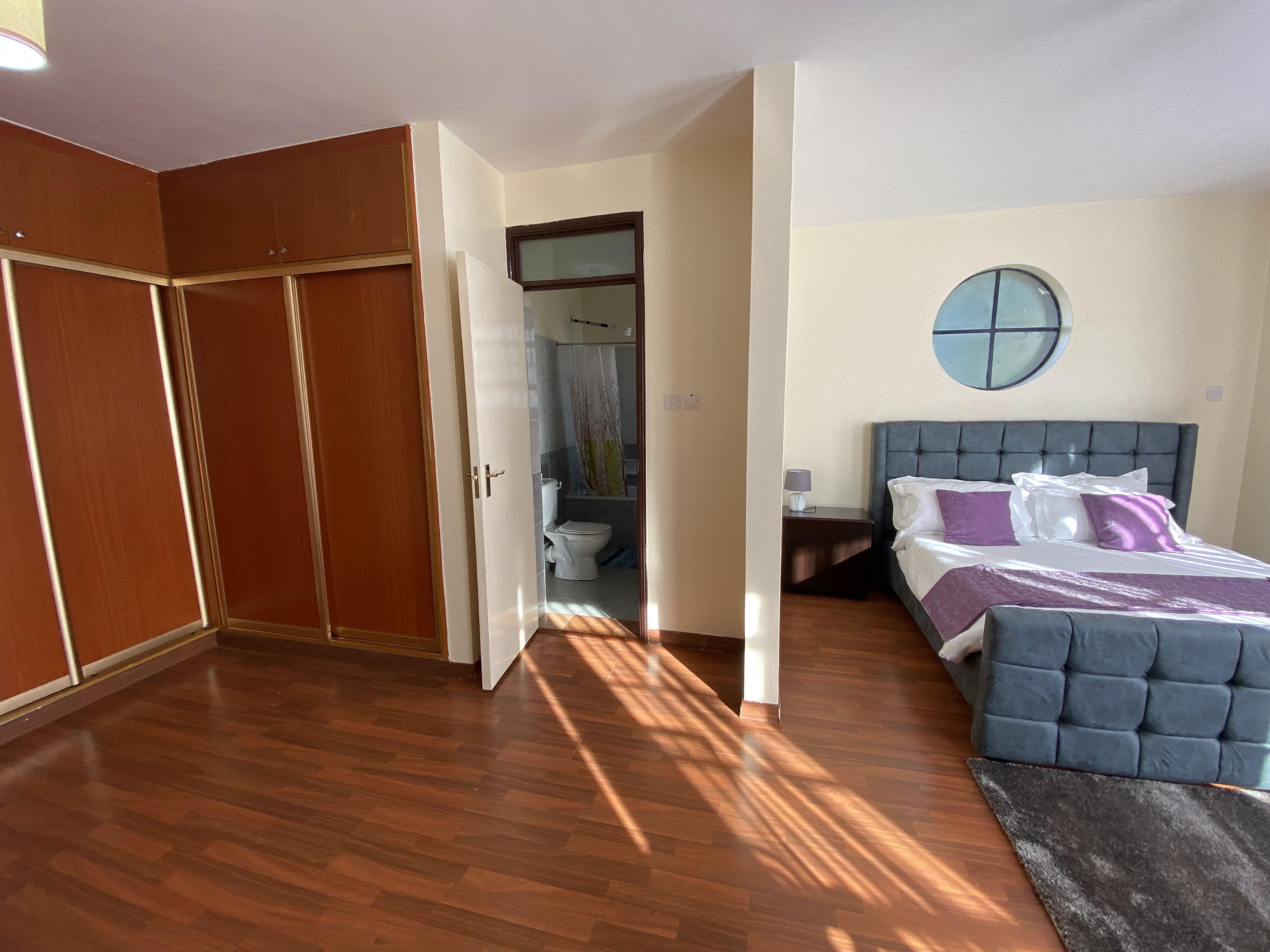 Een slaapkamer met een bed, nachtkastje, spiegel en kledingkast.