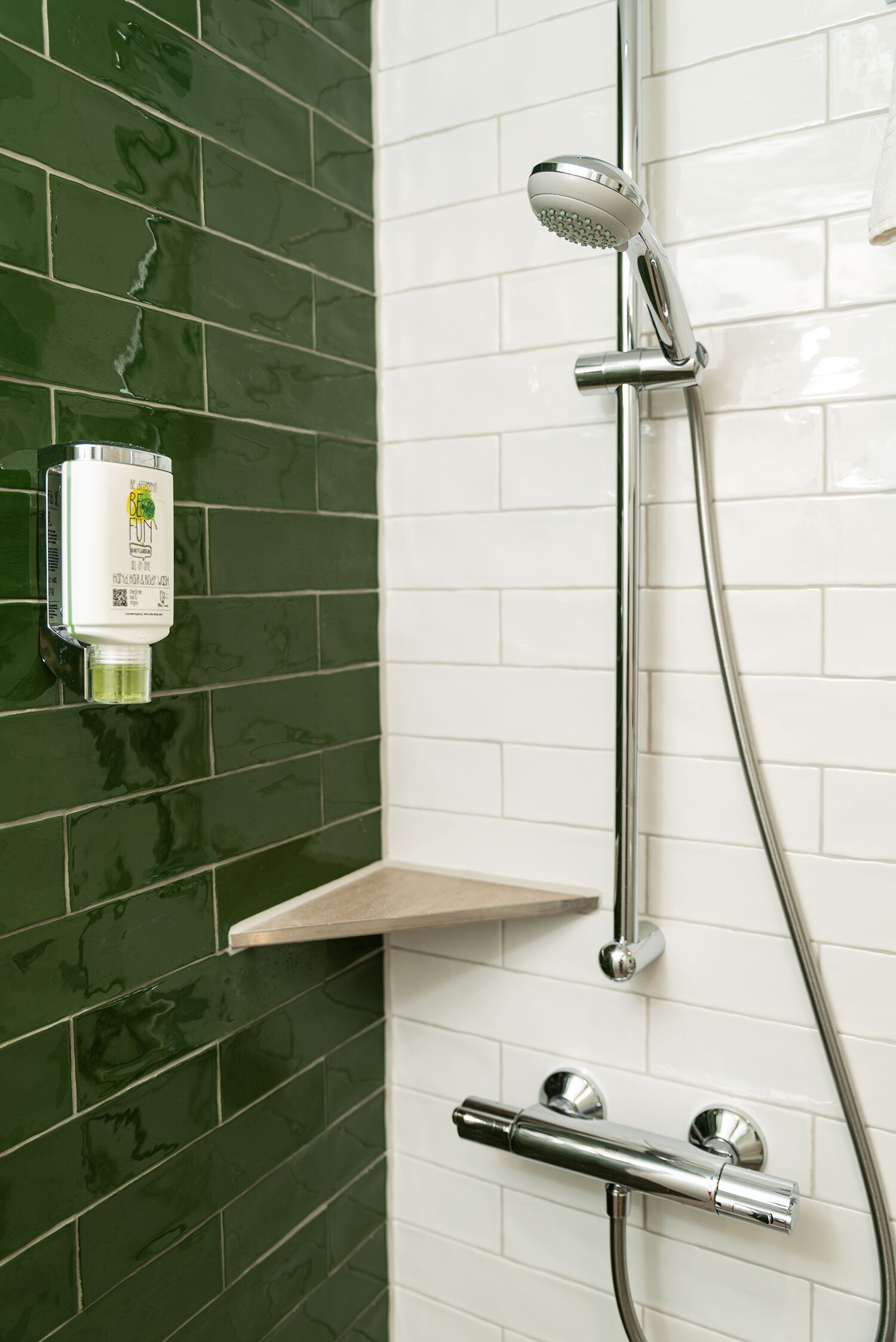 A shower with a handheld showerhead, a wall-mounted control panel, and a chrome faucet.