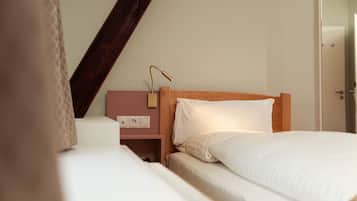 Een hotelkamer met een houten hoofdeinde, een nachtkastje met een lamp en een stopcontact.