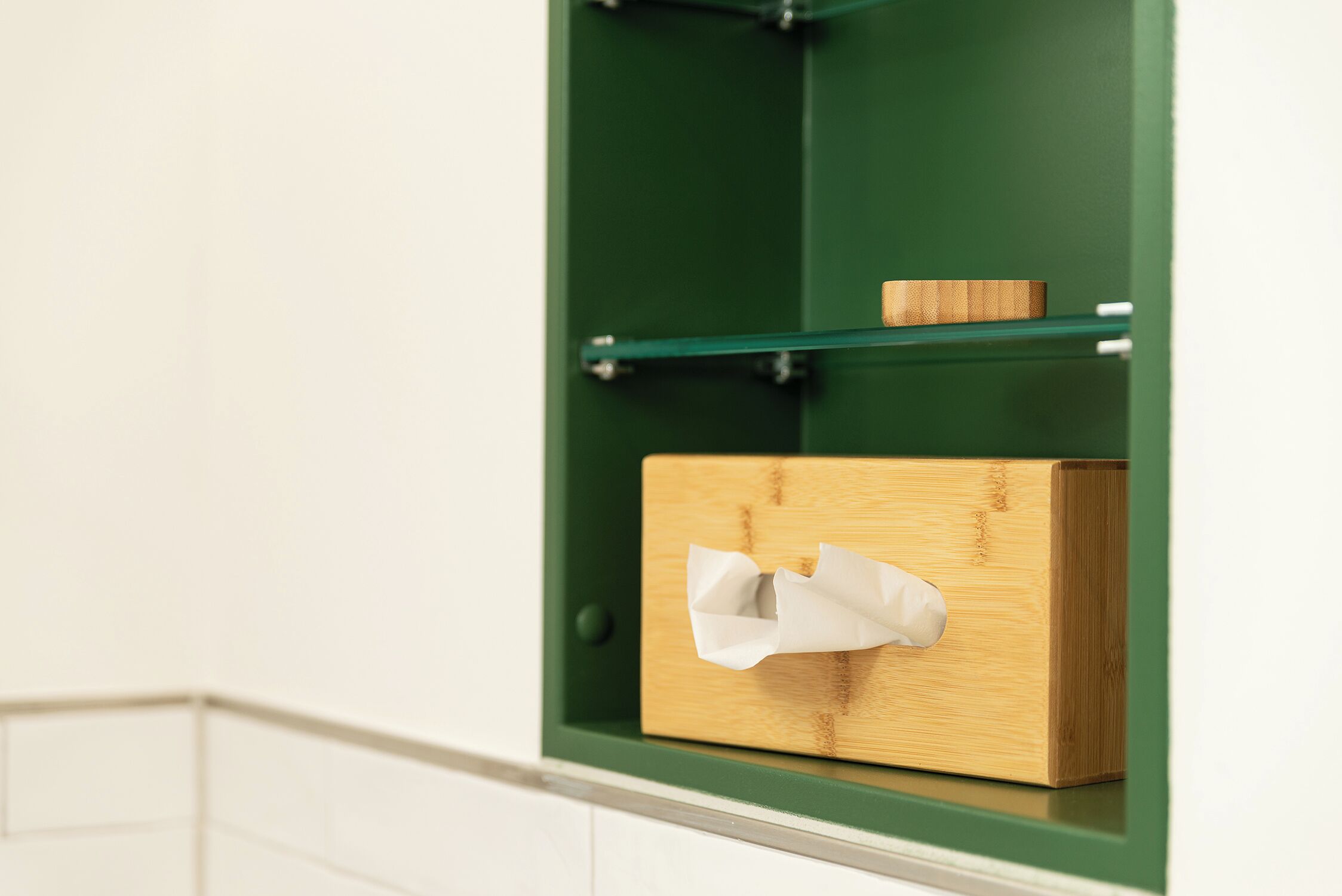 Un mueble de baño verde con una caja de madera que contiene un pañuelo.