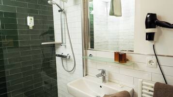 Un baño con ducha, lavabo y un secador de pelo en la pared.