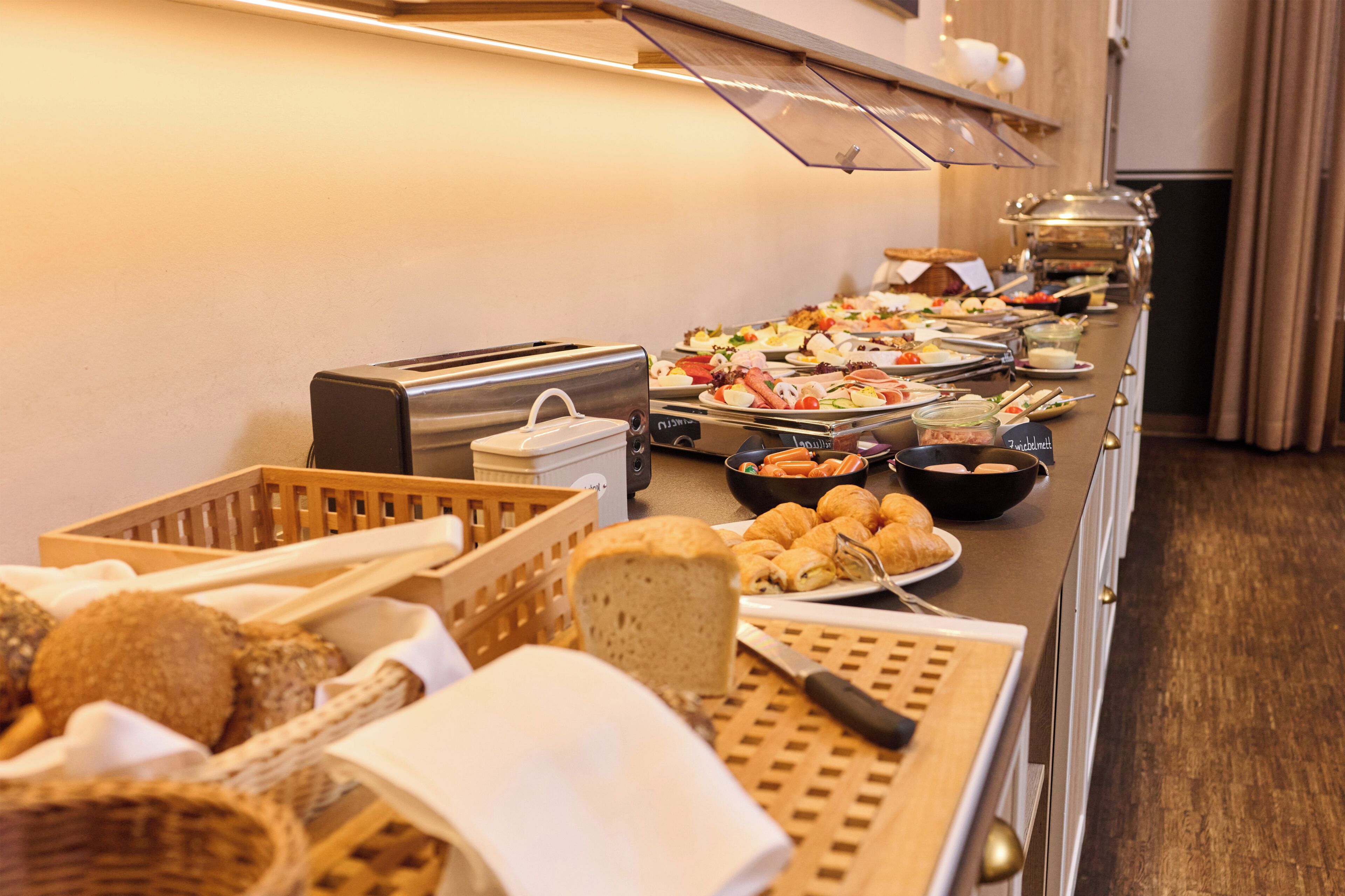 A buffet with various food items, a toaster, and a knife on a table.