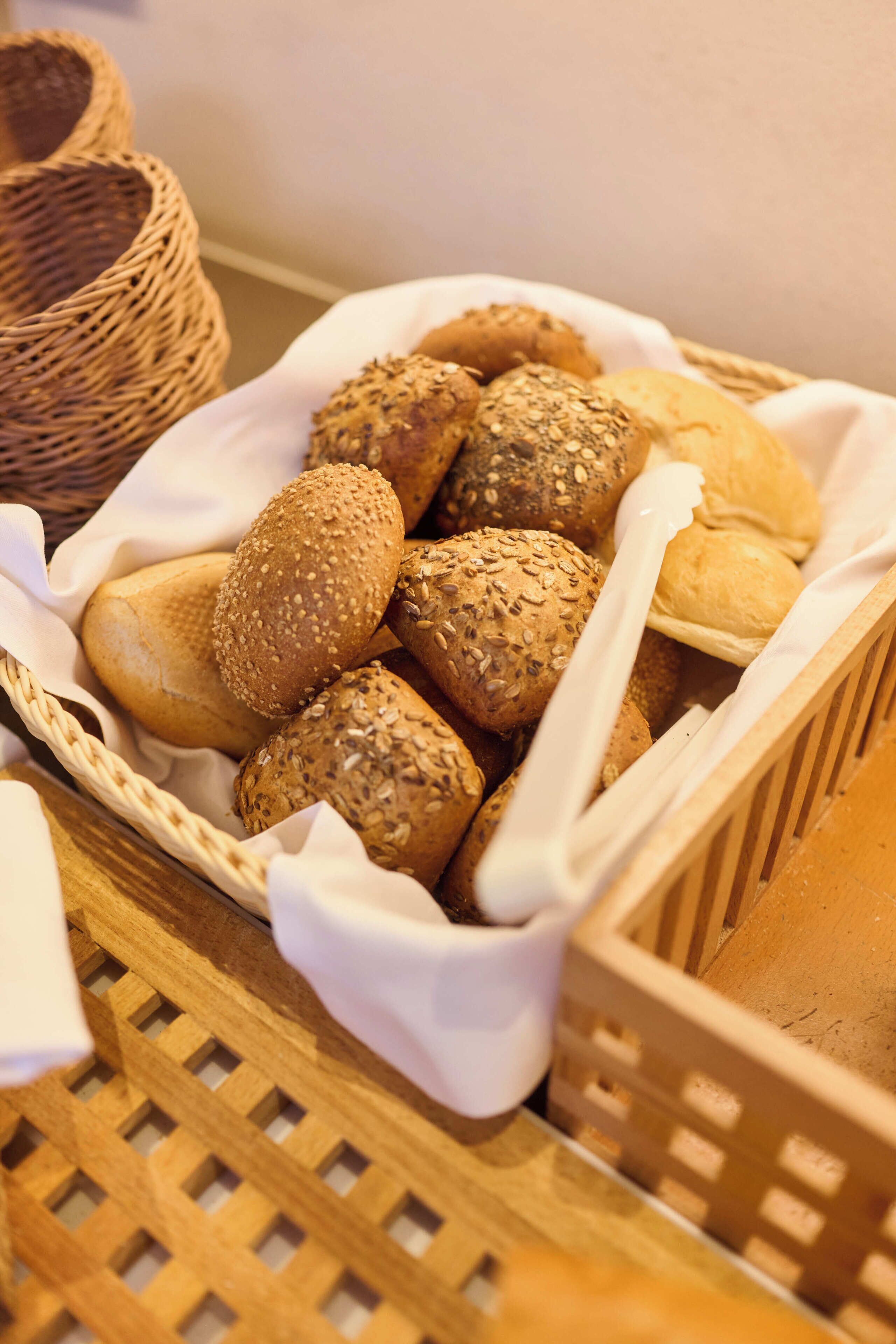 Ein Korb mit verschiedenen Brotsorten und ein Korbschrank im Hintergrund.