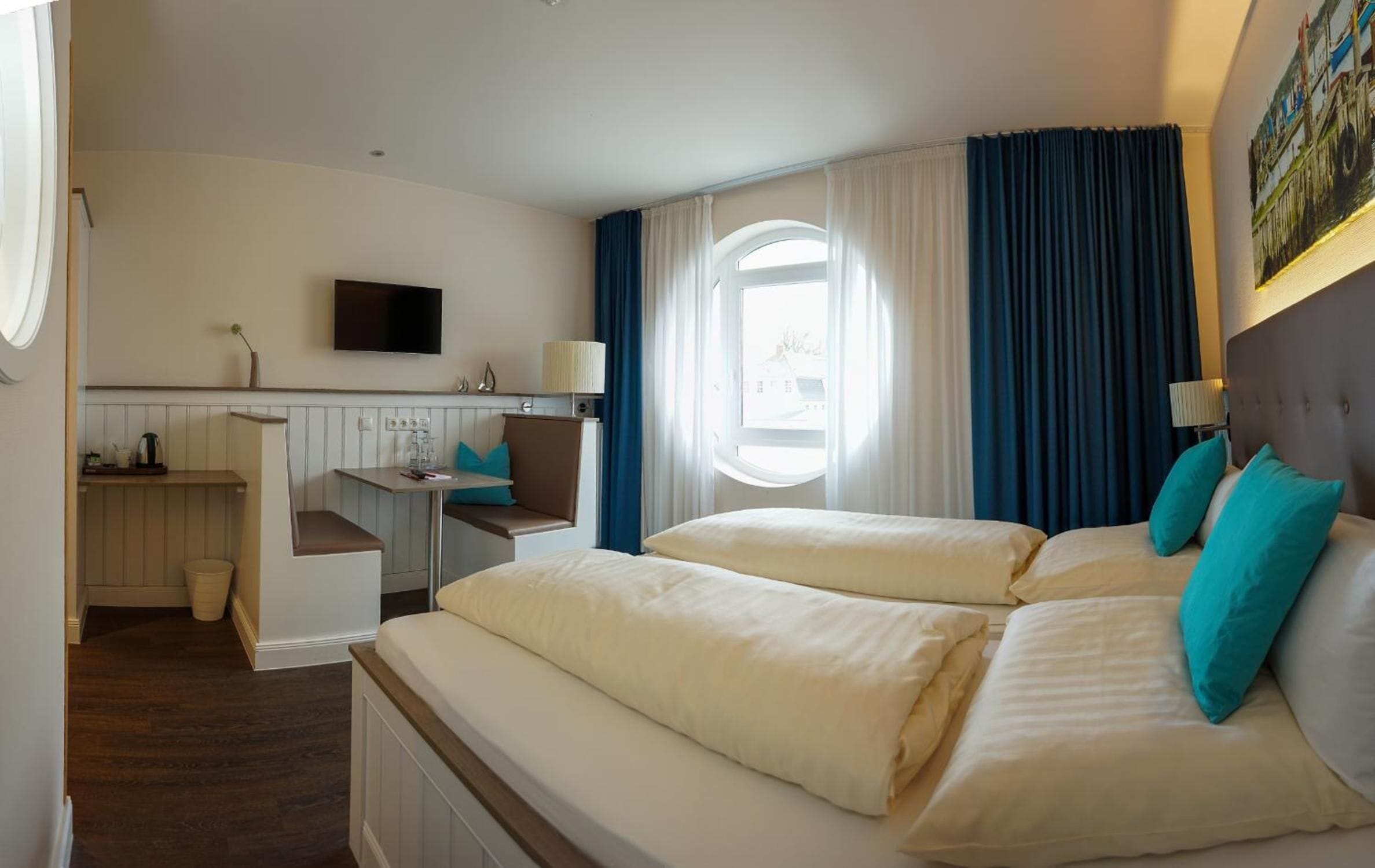 Een hotelkamer met een bed, een bureau, een stoel, een televisie en een raam met gordijnen.