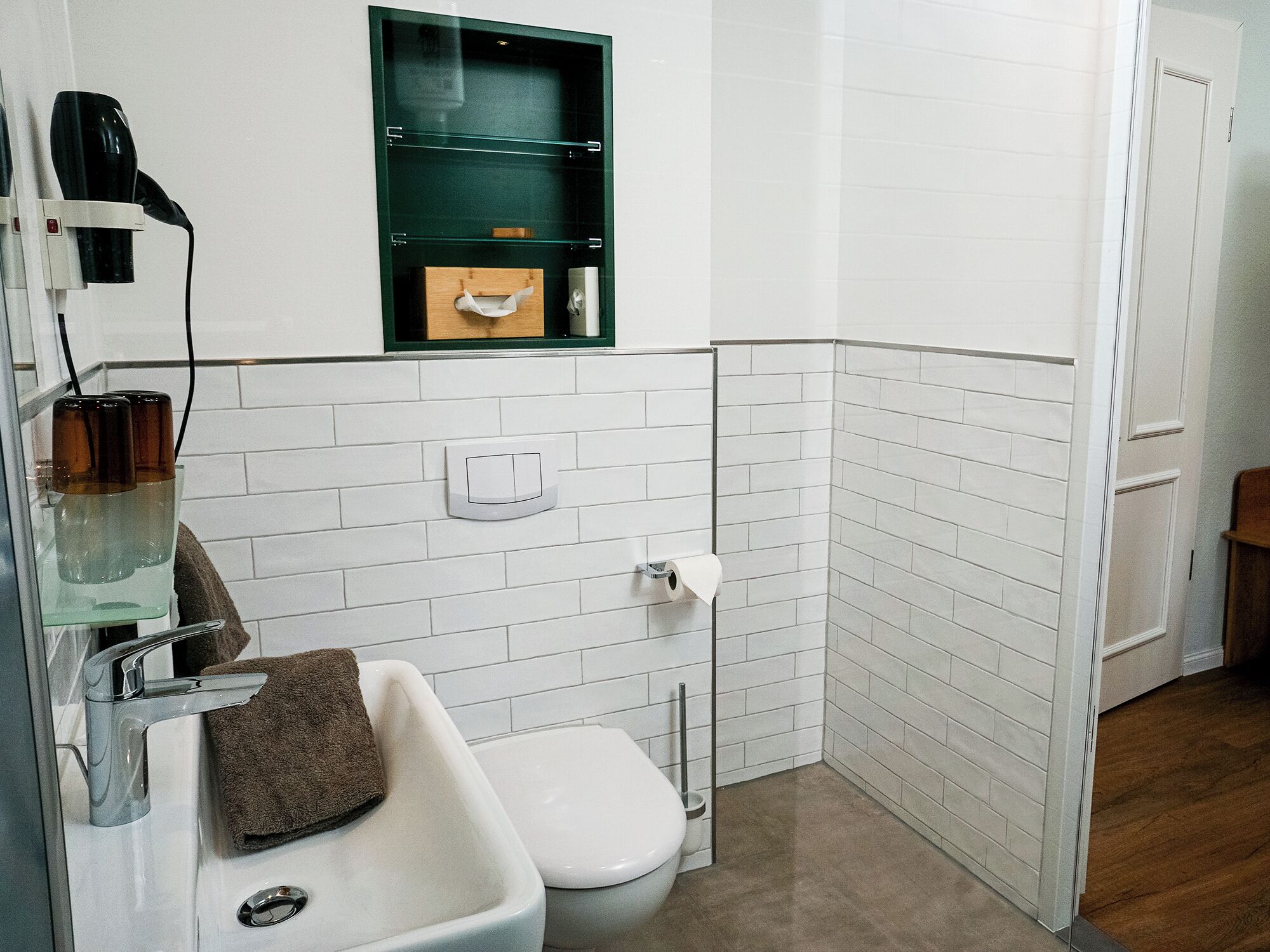 Ein Badezimmer mit Waschbecken, Toilette und einem grünen Medikamentenschrank über dem Spiegel.