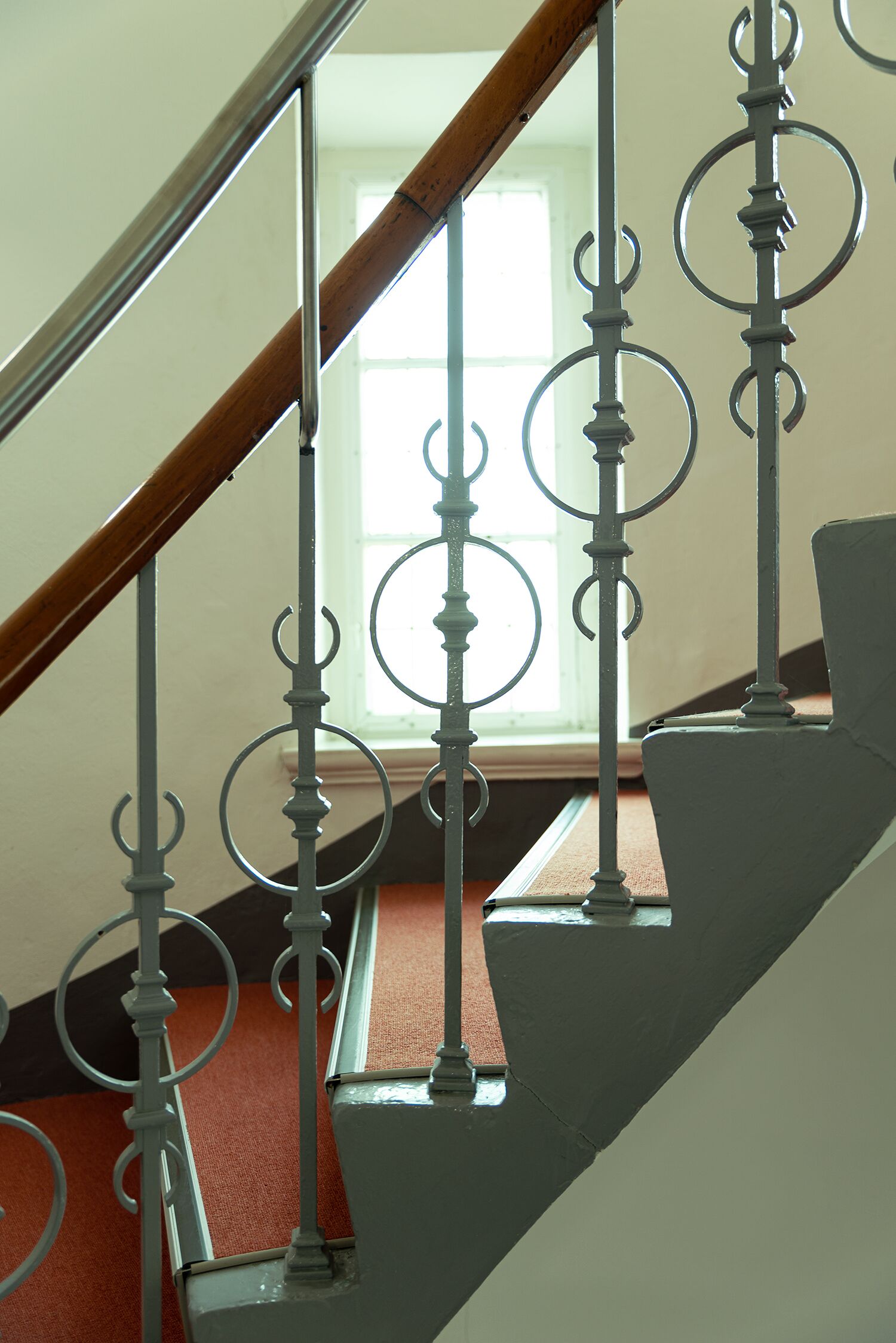 Una escalera con barandales de metal ornamentados y un pasamanos de madera.