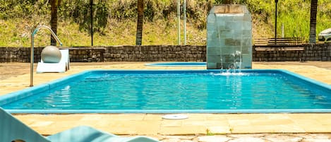 Una piscina al aire libre, sillones reclinables de piscina