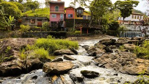 Un ruisseau qui serpente entre les rochers, avec des maisons en arrière-plan.