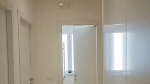 A hallway with a patterned floor, white doors, and a window with blinds. - B&B Siracusa Holidays (Syracuse)