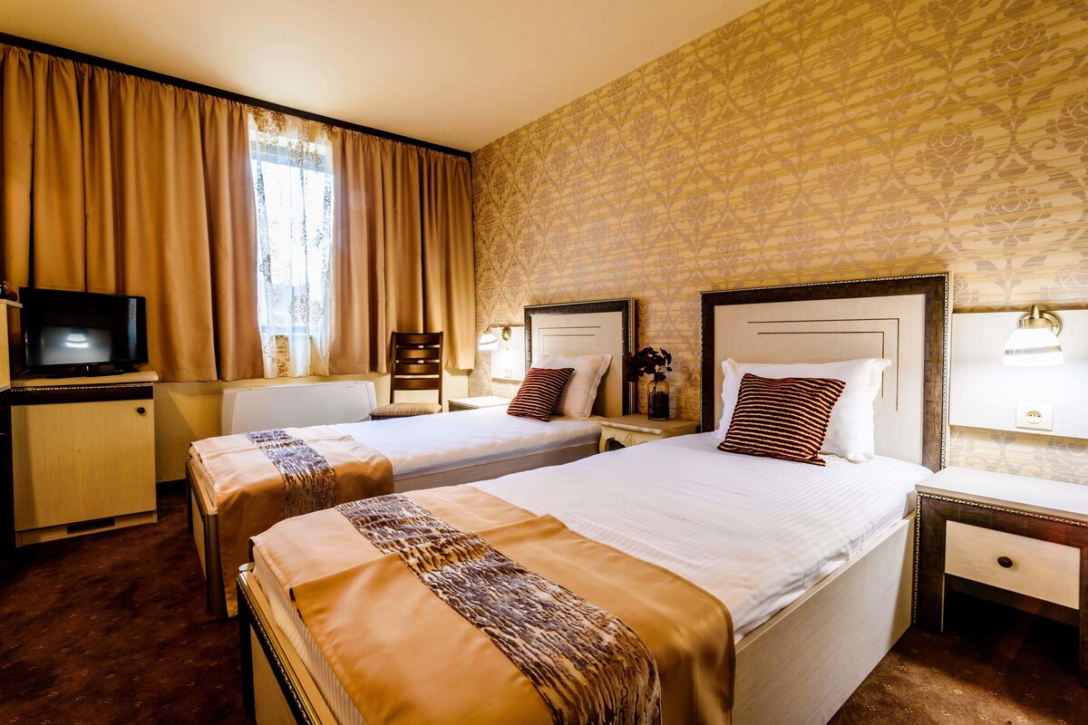 Ein Hotelzimmer mit zwei Betten, einem Fernseher, einem Schreibtisch und einem Stuhl.