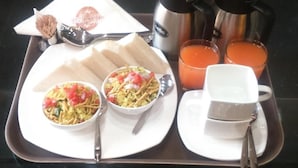 Una bandeja con un sándwich, dos tazones de comida, una taza de té y dos termos de jugo de naranja.