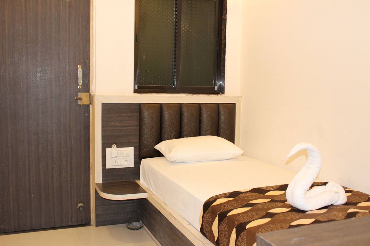 Un dormitorio con cama, ventana, puerta y una mesita de noche.