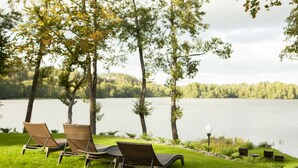 A lakeside setting with lounge chairs and a lamp post. - Leśny Dwór (Suleczyno)