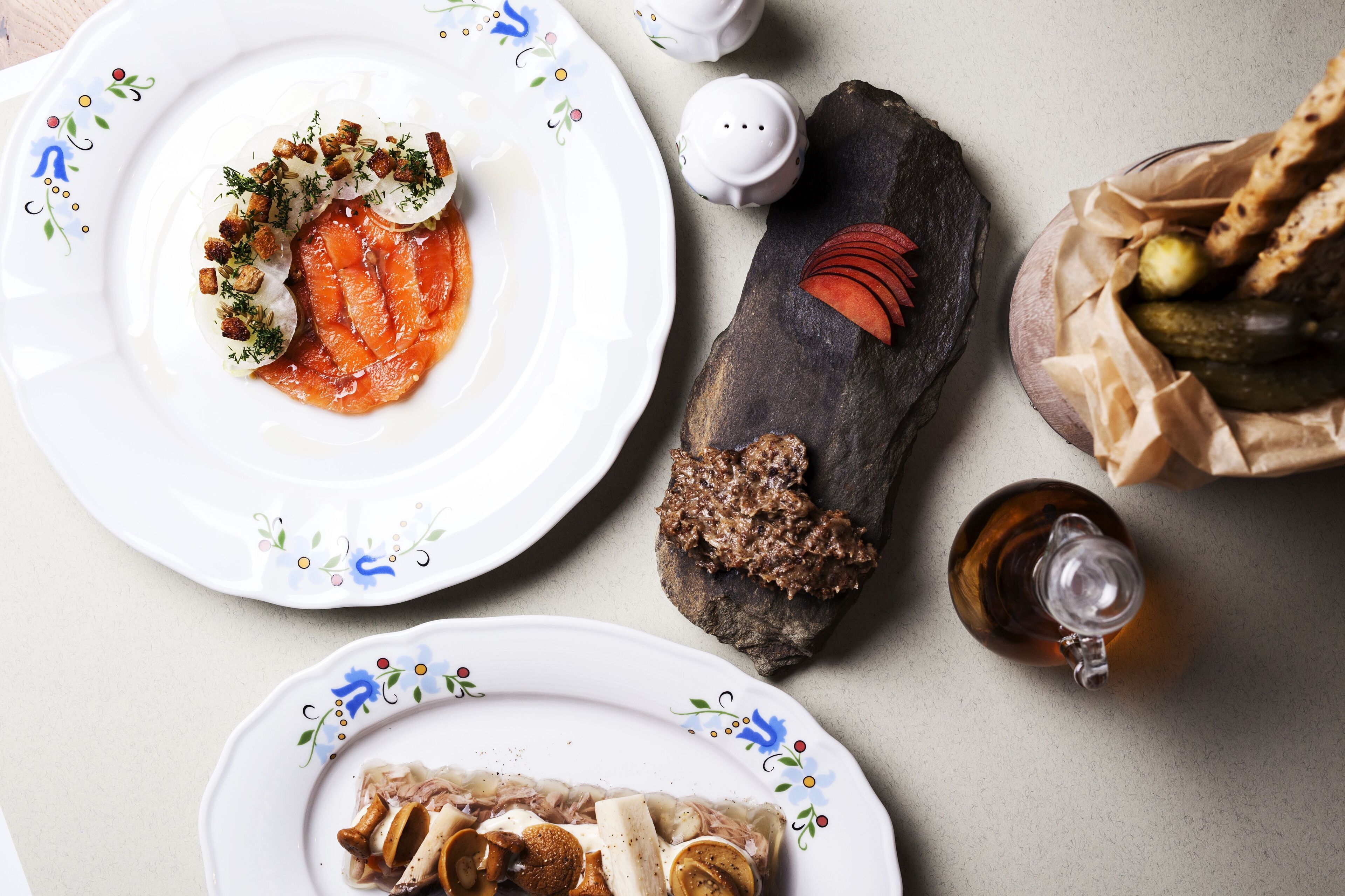 Una mesa con platos de comida, un salero, un pimentero y un vaso de bebida.
