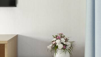 A minimalist room with a wooden desk, a white vase with flowers, and framed botanical illustrations on the wall.