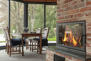 A cozy outdoor seating area with a fireplace, wooden chairs, and a table.