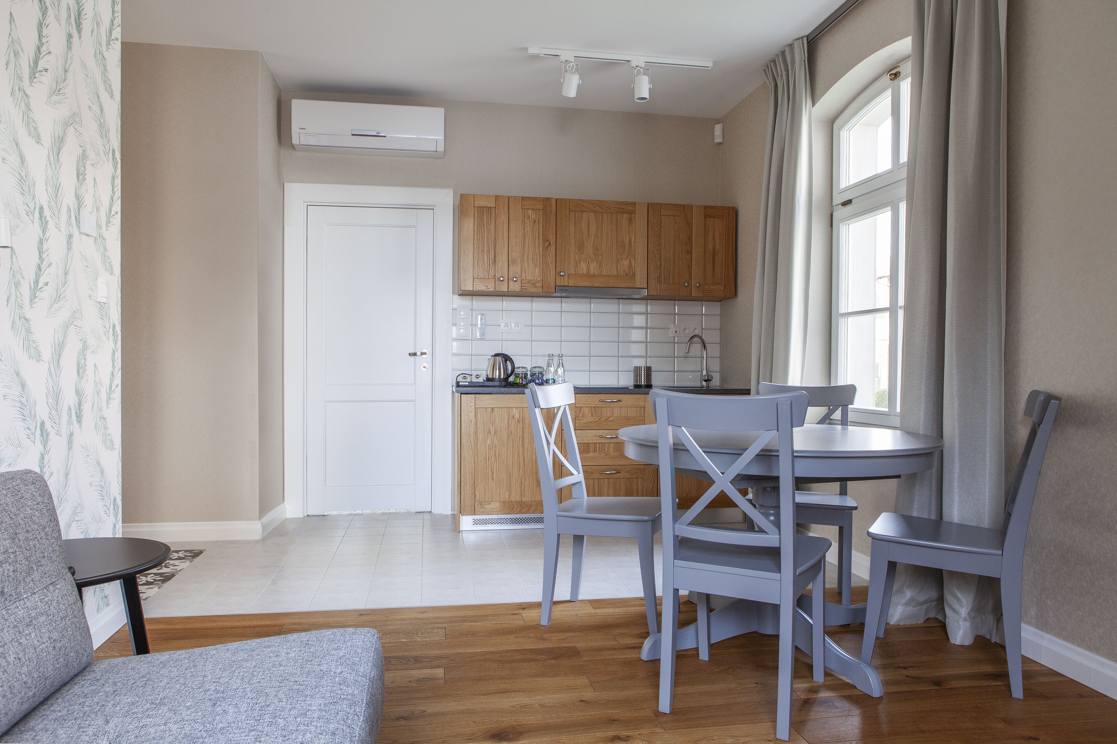 Une cuisine moderne avec des meubles en bois, un plan de travail blanc et un coin repas avec des chaises grises.