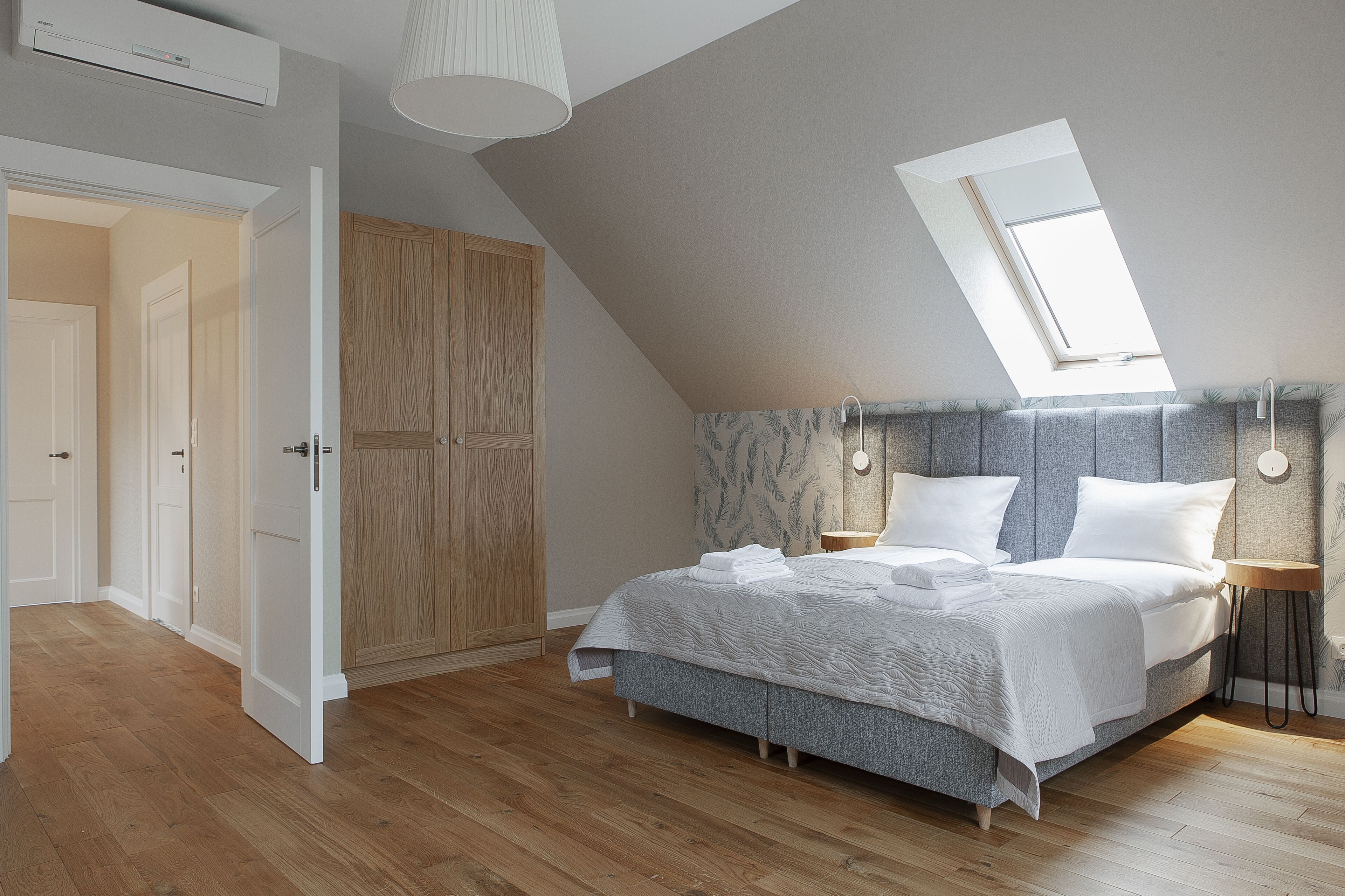 Een slaapkamer met een bed, dakraam, kledingkast en nachtkastje.