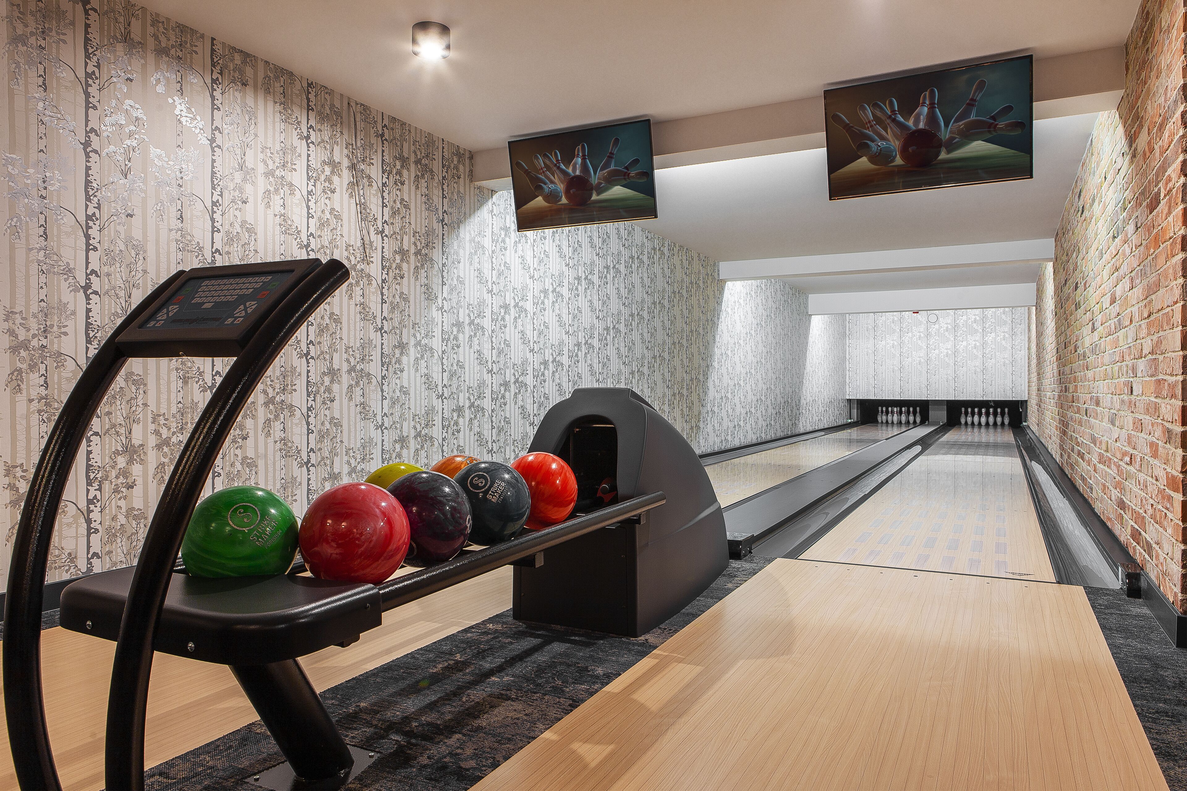 Bolera de diseño moderno, con piso de madera, una pista de bolos y un porta bolas.