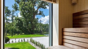 A modern interior with a wooden bench and a large window offering a view of a well-maintained garden and a pathway. - Leśny Dwór (Suleczyno)