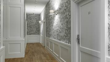 A hallway with patterned wallpaper, a wooden floor, and a door marked with the number 23.