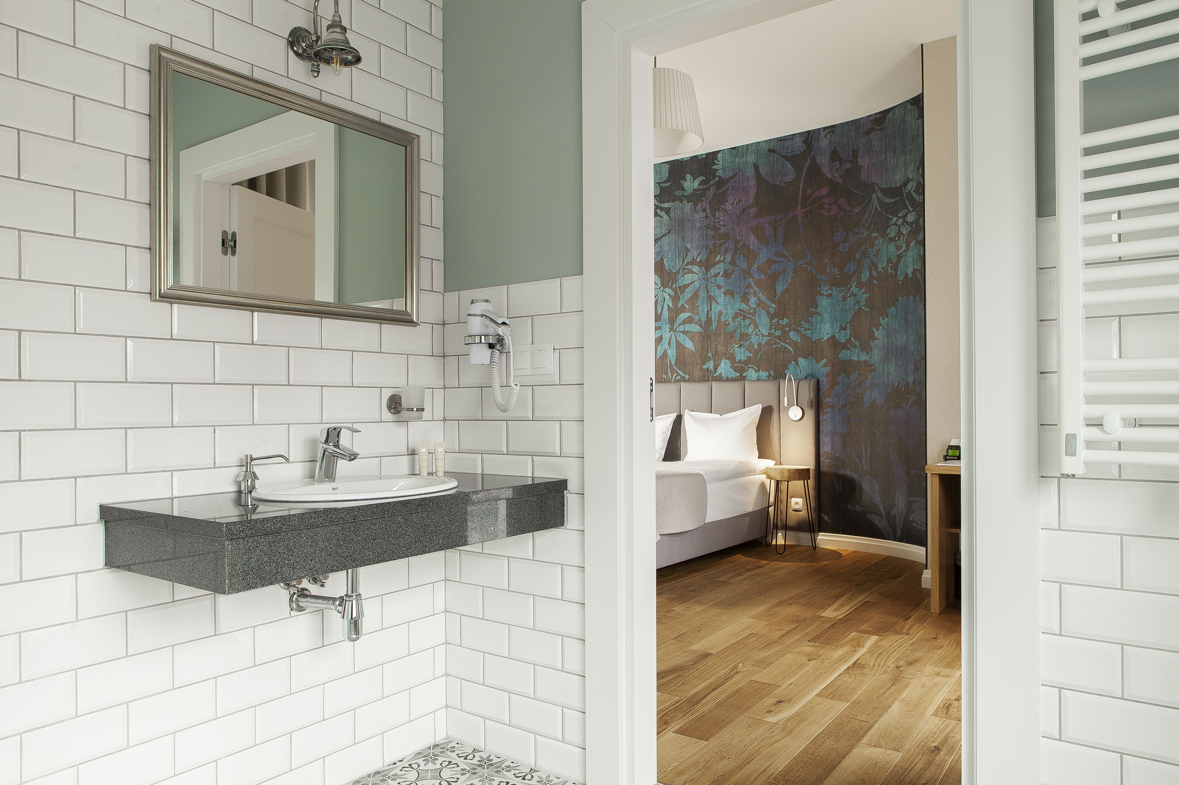 A modern bathroom with white subway tiles, a granite countertop sink, and a large mirror.