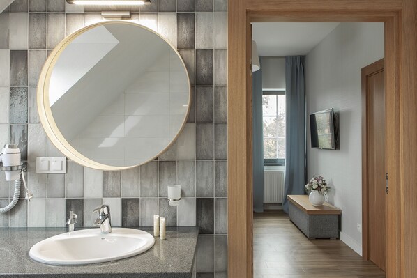 A modern bathroom with a round mirror, a sink, and a towel rack. - Leśny Dwór (Suleczyno)
