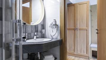 Ein modernes Badezimmer mit Duschkabine aus Glas, einem weißen Waschbecken und einem Badmöbelkorpus aus Holz.