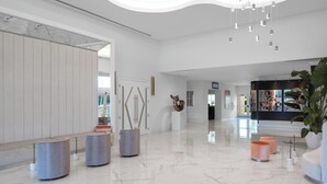 Um hall amplo com teto alto, piso de mármore e instalações de arte moderna.