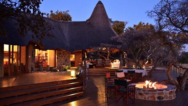 A thatched-roof building with a wooden deck and outdoor seating area. - Zangarna Game Lodge (Vaalwater)