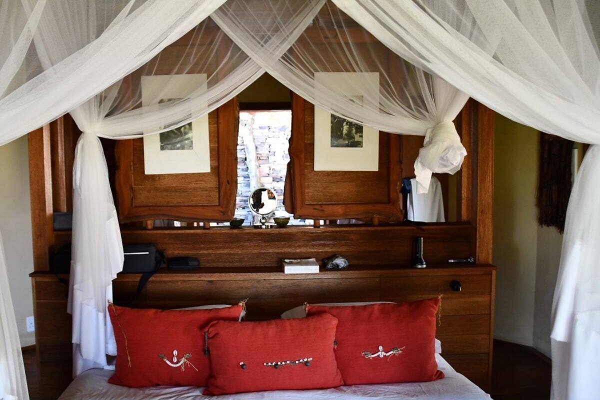 A bedroom with a canopy bed, wooden headboard, and a mirror above the dresser.