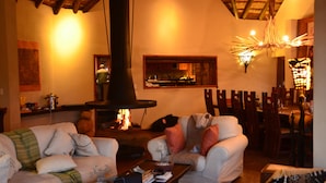 A cozy living room with a fireplace, comfortable seating, and a dining area. - Zangarna Game Lodge (Vaalwater)
