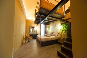 A bedroom with a bed, a chair, a desk, and a staircase.