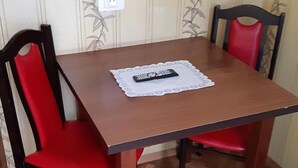 A dining table with a remote control on a placemat, surrounded by red chairs. - Hostel mPark Chorzow (Chorzow)
