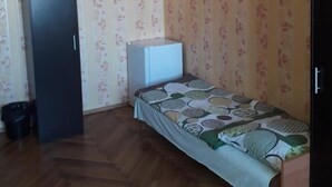 A small room with a bed, a wardrobe, and a radiator. - Hostel mPark Chorzow (Chorzow)