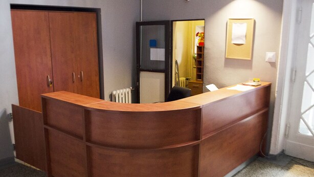 A reception desk with a wooden finish, a radiator, and a door leading to another room. - Hostel mPark Chorzow (Chorzow)
