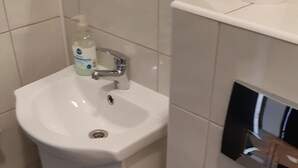 A bathroom with a white sink, a toilet, and a cabinet. - Hostel mPark Chorzow (Chorzow)