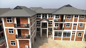 A multi-story residential building with a central courtyard, balconies, and a uniform roof design. - Royal Baron Hotel (Kumasi)