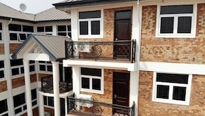 A multi-story building with balconies, brick walls, and multiple windows. - Royal Baron Hotel (Kumasi)