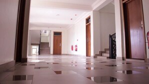 A spacious hallway with a tiled floor, wooden doors, and a staircase leading to another level. - Royal Baron Hotel (Kumasi)