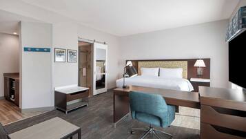 A hotel room with a bed, desk, chair, and a television.