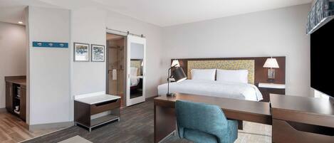 A hotel room with a bed, desk, chair, and a television.