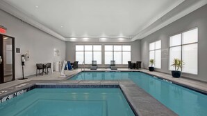 A large indoor swimming pool with clear water, surrounded by lounge chairs and potted plants. - Hampton Inn & Suites Farmers Branch Dallas (Farmers Branch)
