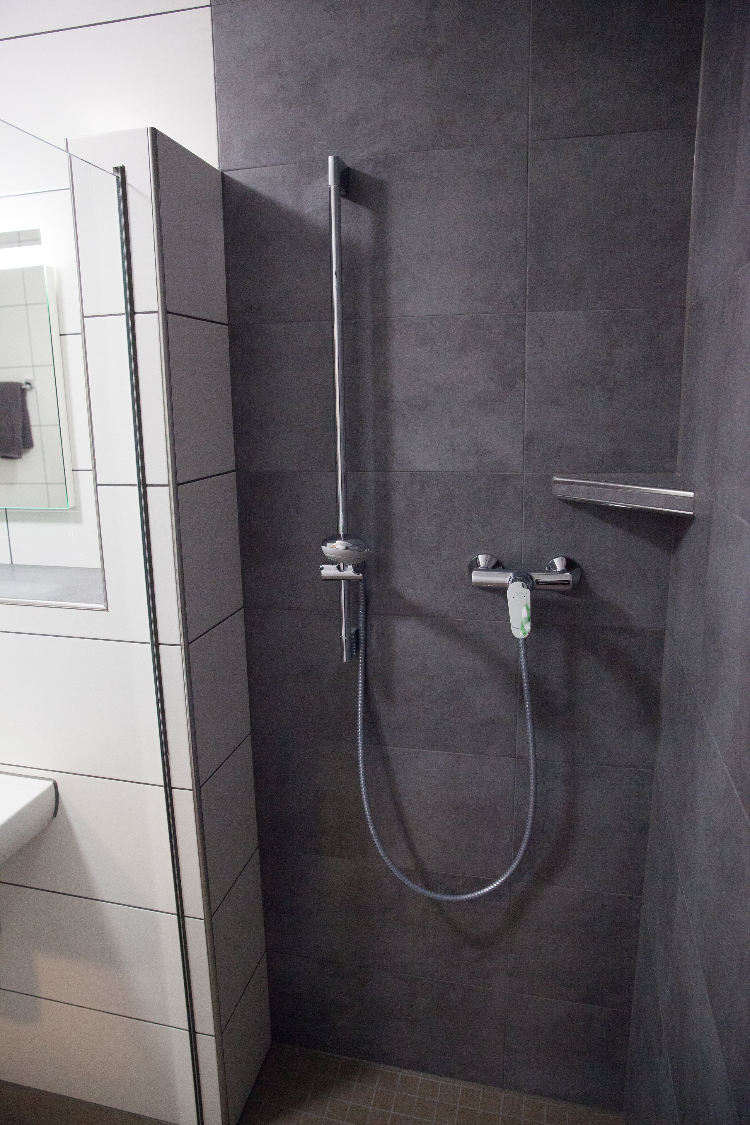 Une salle de bain moderne avec une douche, un espace douche vitré et un lavabo blanc.