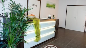 Een receptiebalie met een plant, een schaal fruit en een bordje met de tekst 'Büro'.