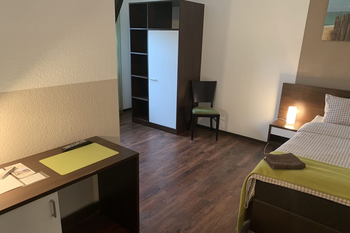 Een hotelkamer met een bed, een bureau, een stoel en een kledingkast.